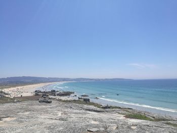 Scenic view of beach against clear blue sky