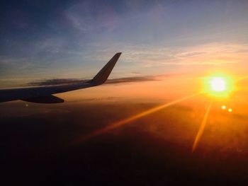 Airplane wing against dramatic sky during sunset