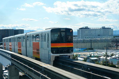 Train at railroad station in city against sky