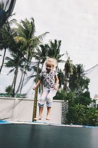 Portrait of girl jumping over trampoline against trees