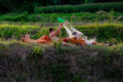 Boys playing water on friend at farm