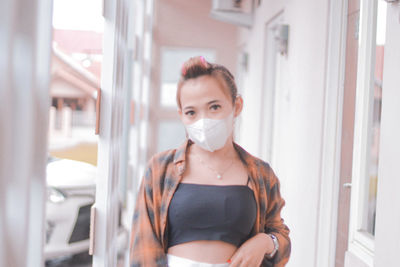 Young woman wearing mask while standing in bathroom