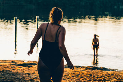 Rear view of woman on field against lake