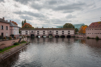 Arch bridge over river by buildings against sky