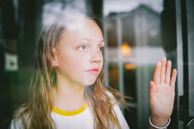 Girl looking away seen through glass window