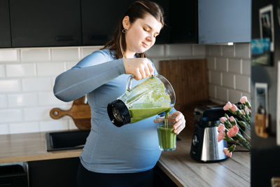 Green smoothies recipes for pregnancy and postpartum, prenatal nutrition. pregnant woman preparing