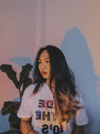 Portrait of young woman standing against wall