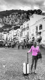 Rear view of woman walking on street against buildings in city