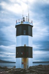 Lighthouse by sea against sky