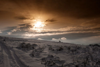Scenic view of snow covered land against sky during sunset