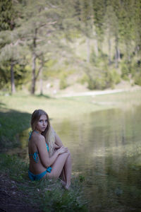 Portrait of young woman sitting on lake