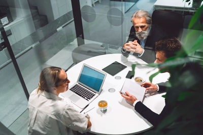 High angle view of man using mobile phone while sitting on table