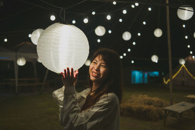 Woman with arms raised standing at night