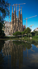 Barcelona cathedral reflecting in lake against blue sky