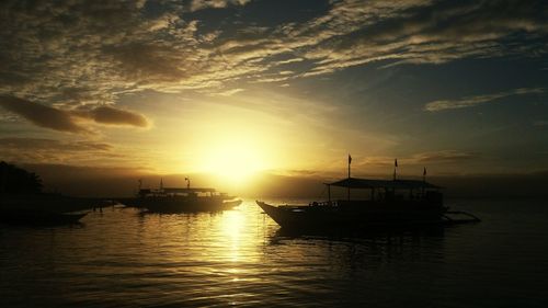 Boats in sea at sunset