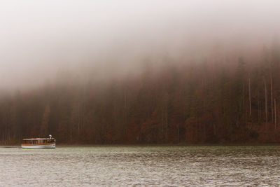 Foggy day on mountain lake with tourist boat