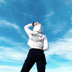 Low angle view of man standing against blue sky