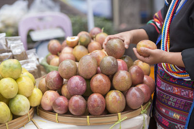 Midsection of woman picking fruits at market stall