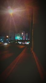 Illuminated road in city against sky at night