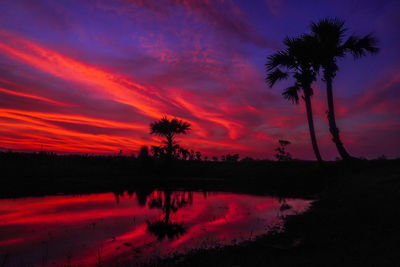 Scenic view of silhouette palm trees against romantic sky at sunset