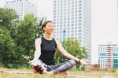 Young smiling woman practice yoga outdoors in the city. new normal social distance. physical 