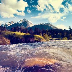 Scenic view of river by mountains against sky