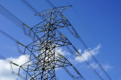 Low angle view of electricity pylon against blue sky