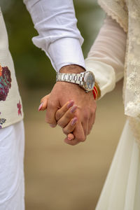 Midsection of bride and groom holding hands