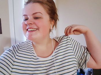 Close-up of smiling young woman sitting at home