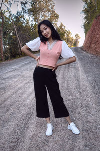 Portrait of young woman standing against tree