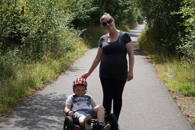 Portrait of woman with son riding vehicle on road amidst trees