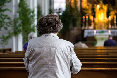 Rear view of woman sitting on bench in heiliggeistkirche