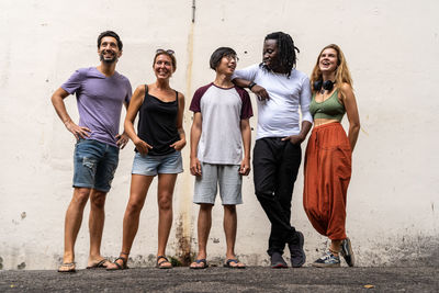 Full length of friends standing against wall