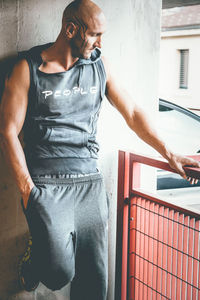 Muscular man leaning on wall in parking lot