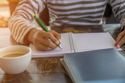 Midsection of woman reading book by table