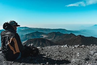 Rear view of man looking at mountains against sky
