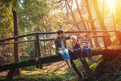 Family sitting on footbridge in public park