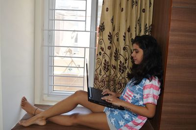 Side view of woman using laptop while sitting at home