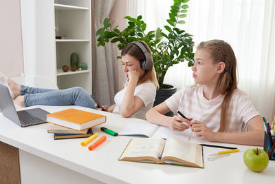 Mother and daughter sitting by desk at home