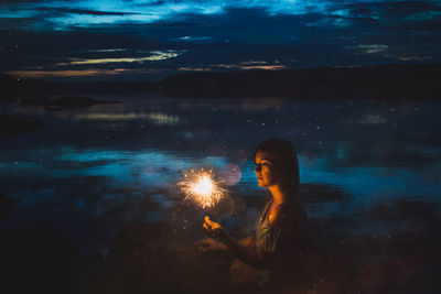 Woman with arms outstretched in water at night