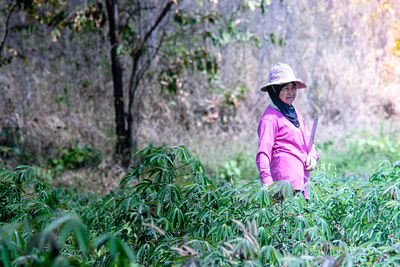 Side view of woman standing amidst plants