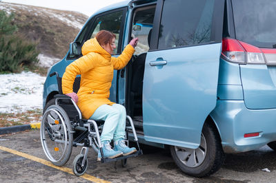 Caucasian woman in a wheelchair gets into the car