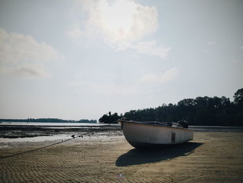 Boat moored on beach against sky