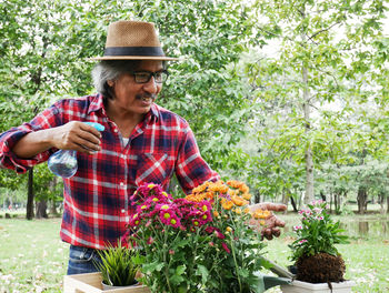Smiling young woman holding red flowering plants