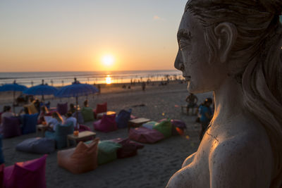 Close-up of statue by sea against sky during sunset