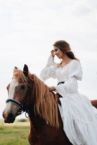 Young woman riding horse on field