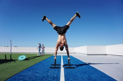 Low angle view of man skateboarding against blue sky