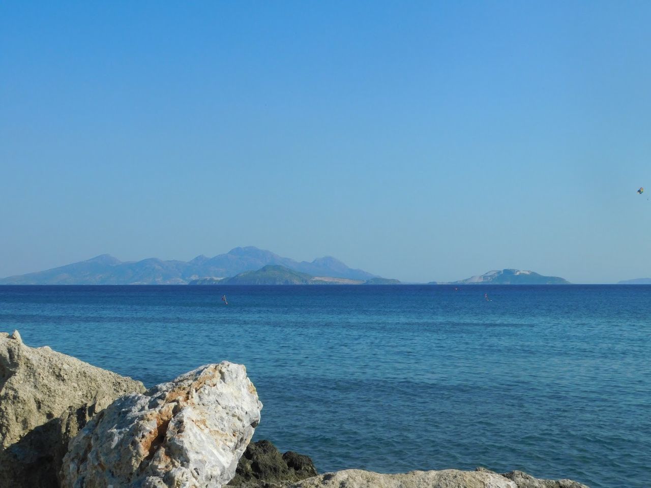 SCENIC VIEW OF SEA AND MOUNTAINS AGAINST CLEAR SKY