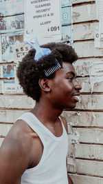 Side view of young woman standing against wall