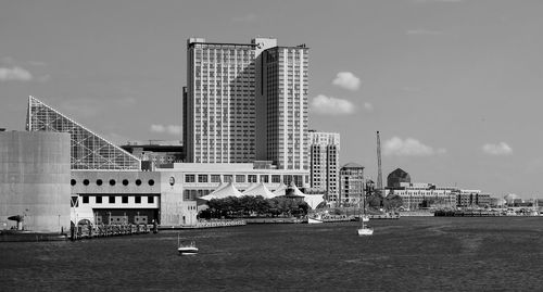 Modern buildings by river against sky in city